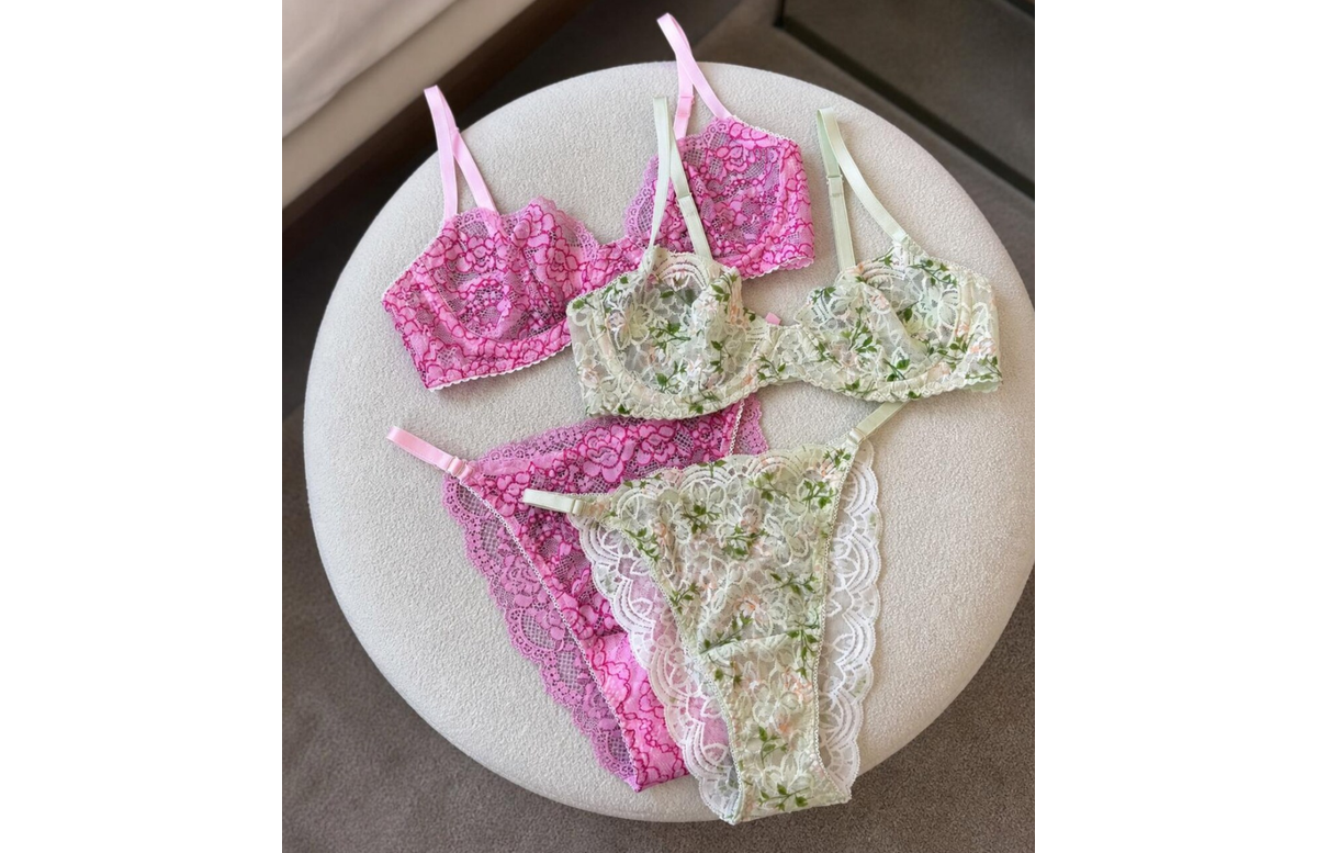 Pink and pale green floral lace lingerie sets arranged on a round upholstered stool